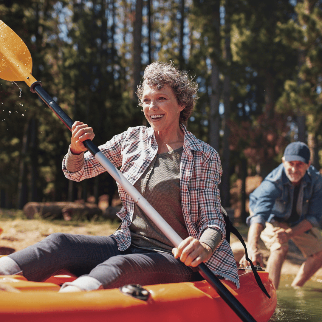 older woman on kayak with man helping launch her, illustrating supplemental health insurance benefits active adults